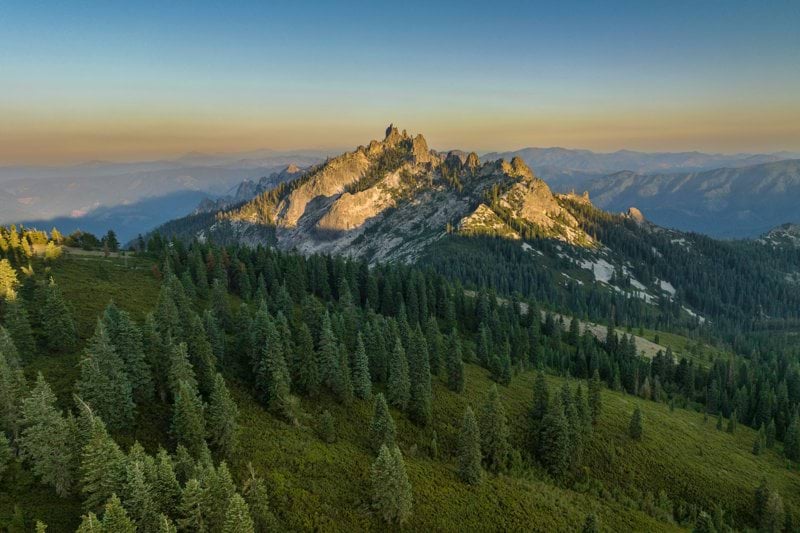 a view of a mountain range with trees in the foreground