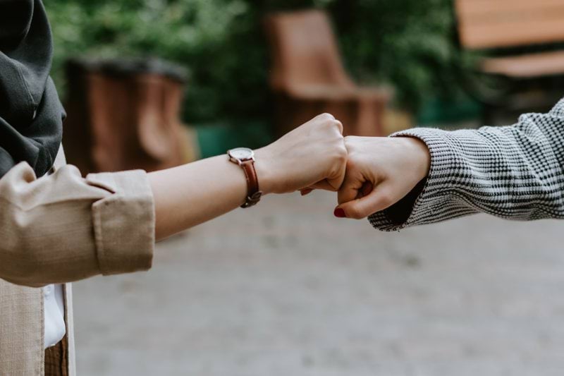 person in black and white long sleeve shirt holding hands with woman in brown coat during