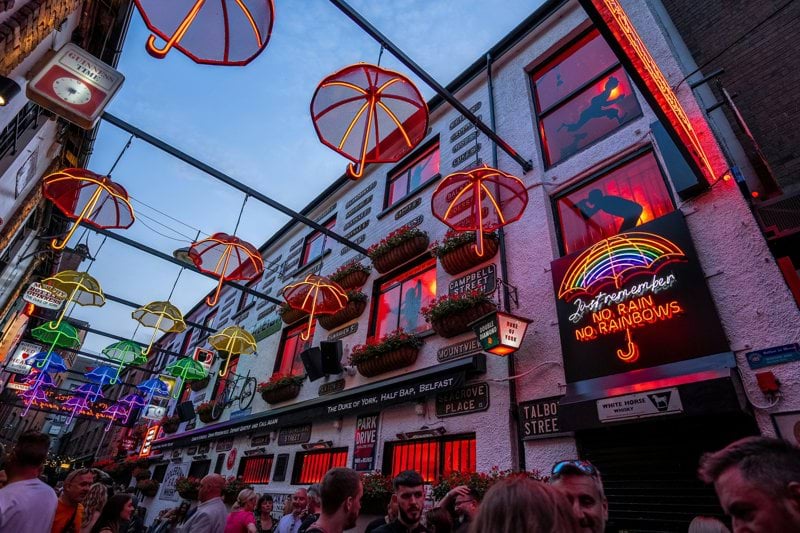 a crowd of people walking down a street next to tall buildings