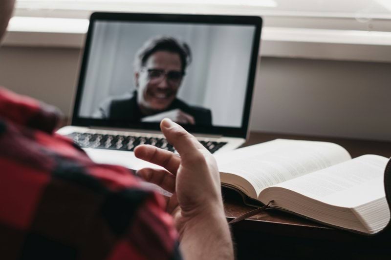 person in red and black plaid long sleeve shirt using black laptop computer