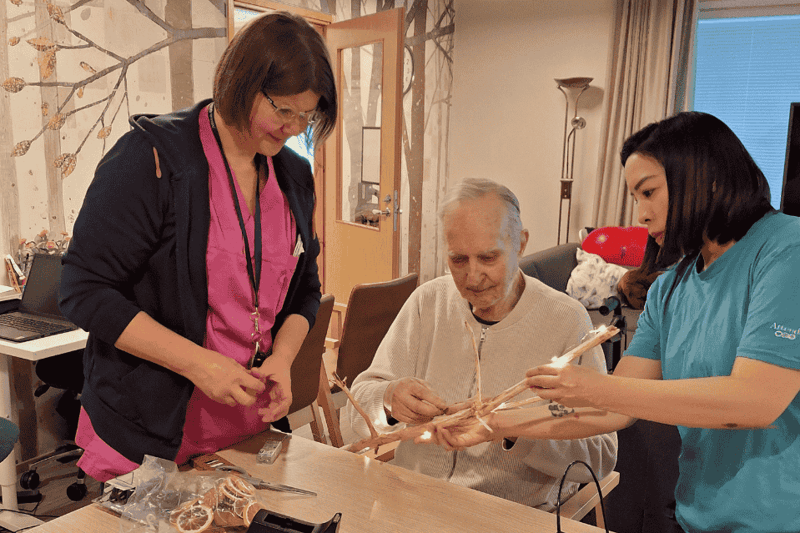 Tupurin hoitaja Mia yhdessä asiakkaan ja toisen hoitajan kanssa hoivakodissa