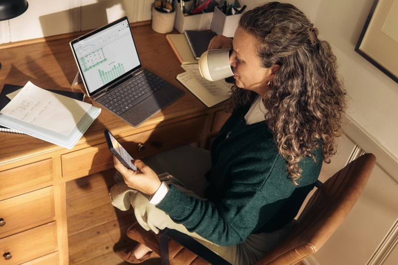 Woman working at a desk with laptop and tablet.
