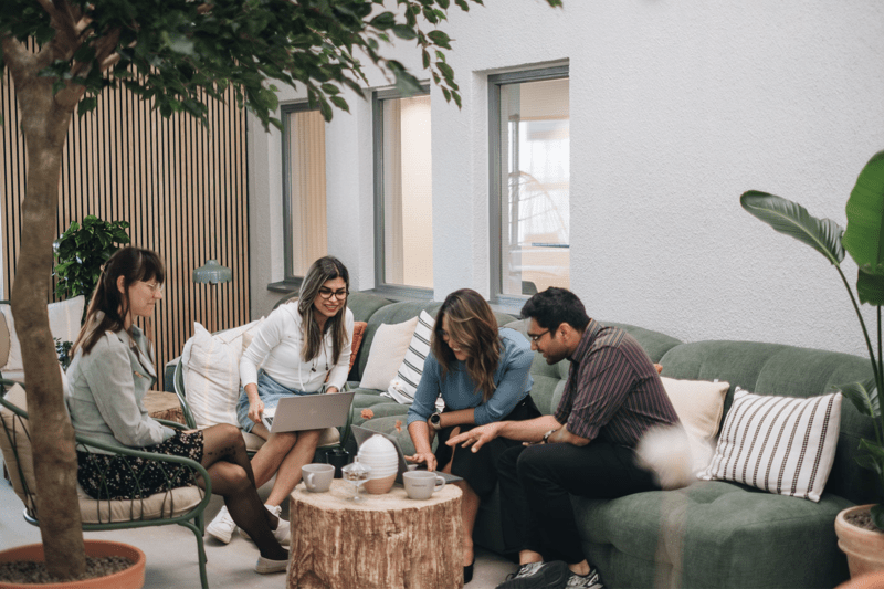 Four people sitting in a lounge area, talking around a table