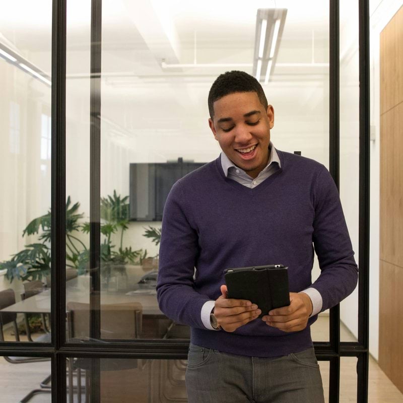 a man standing in an office looking at a tablet