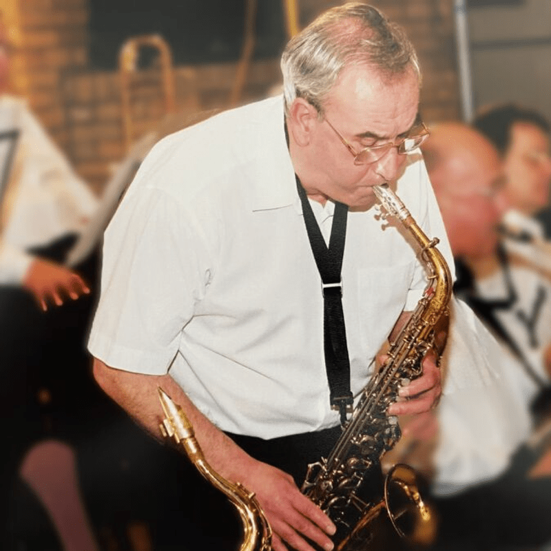 A man wearing glasses, playing the saxophone
