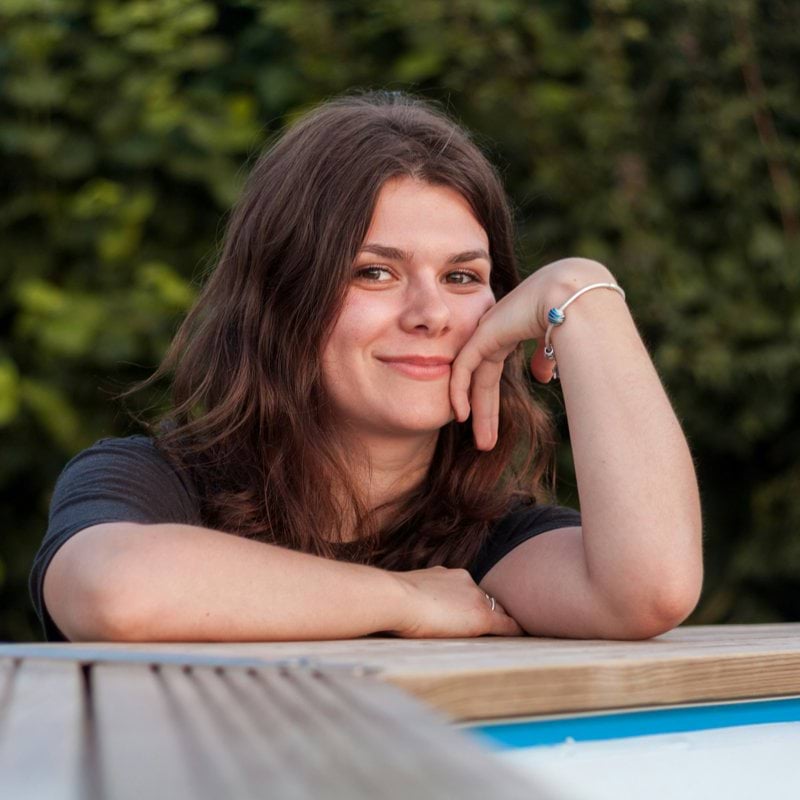 woman's face on her arm while leaning on brown surface
