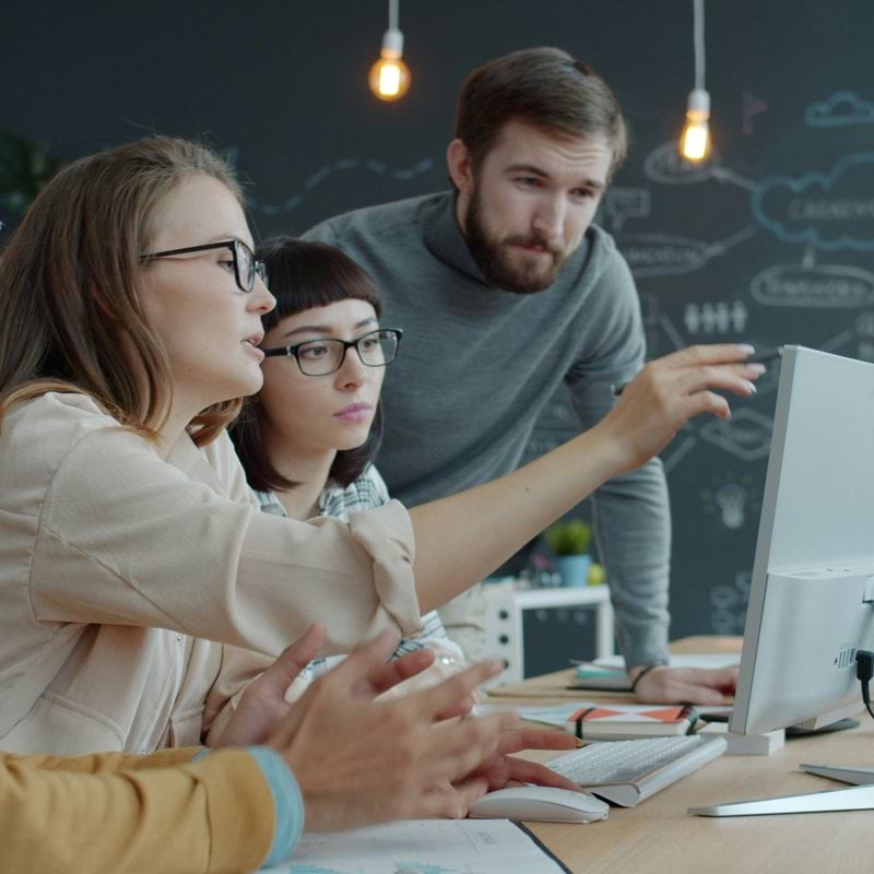 Team collaborating around a computer in an office.