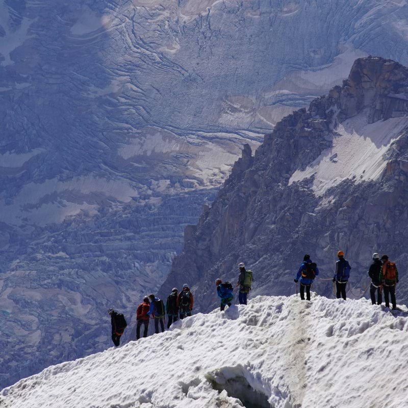 a group of people standing on top of a snow covered mountain