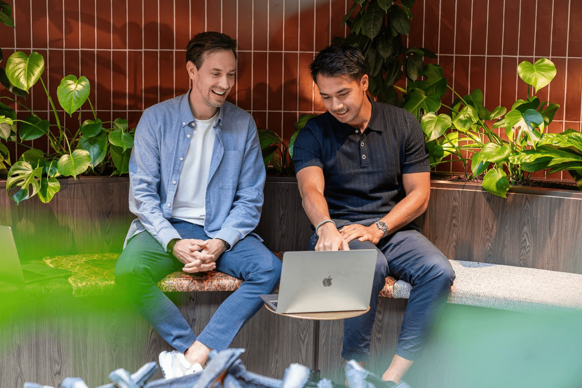 Two colleagues laughing over a laptop by the fireplace in our Eindhoven office