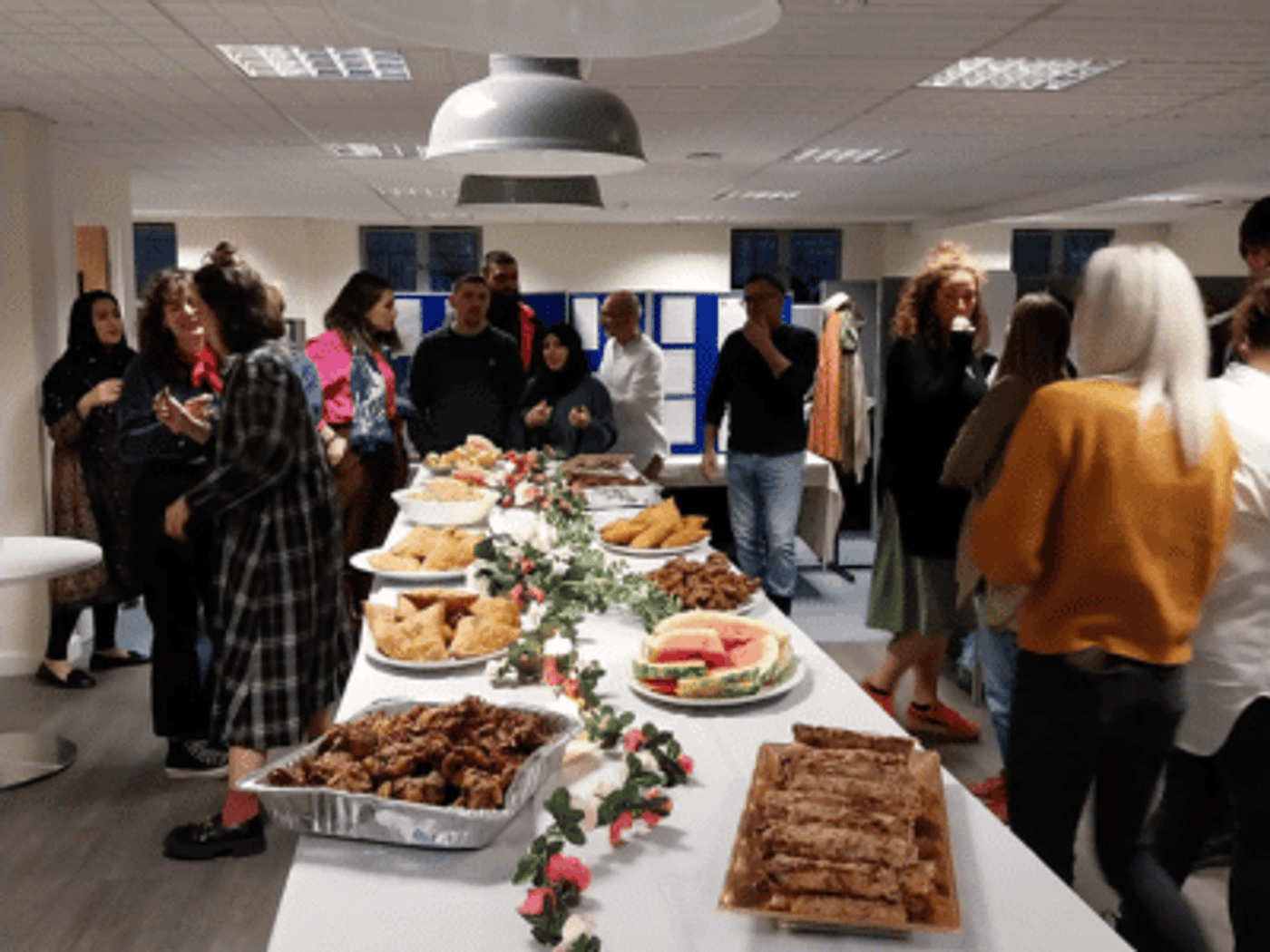 People gathered around a table of food at the Barca-Leeds Iftar event