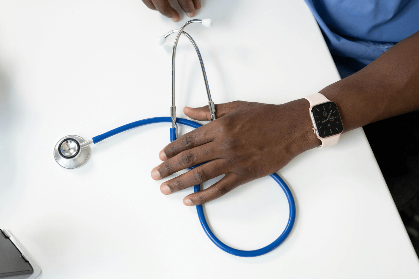 Male nurse holding a stethoscope on a table for a blog about nurse retention in the UK health and social care sector.