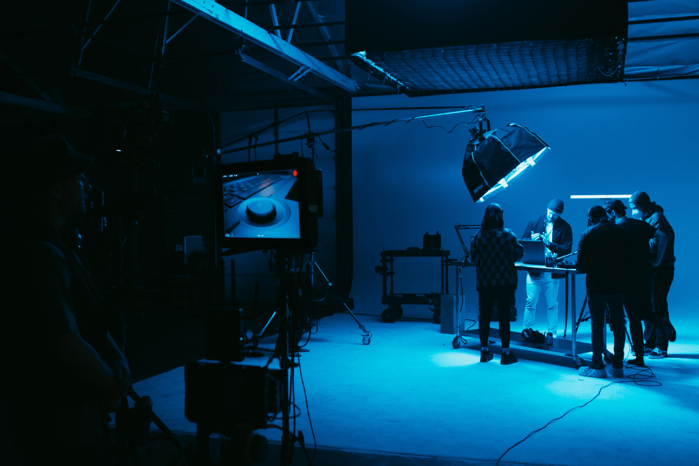 A production shoot where people are surrounded around a table shooting a product in blue lighting