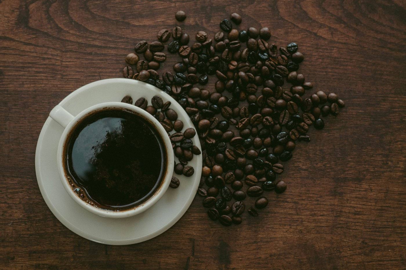 cup of coffee surrounded by beans