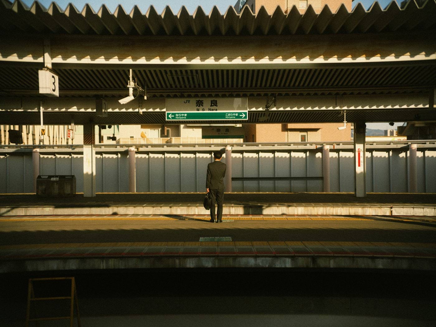 A man stands alone at a japanese train station.