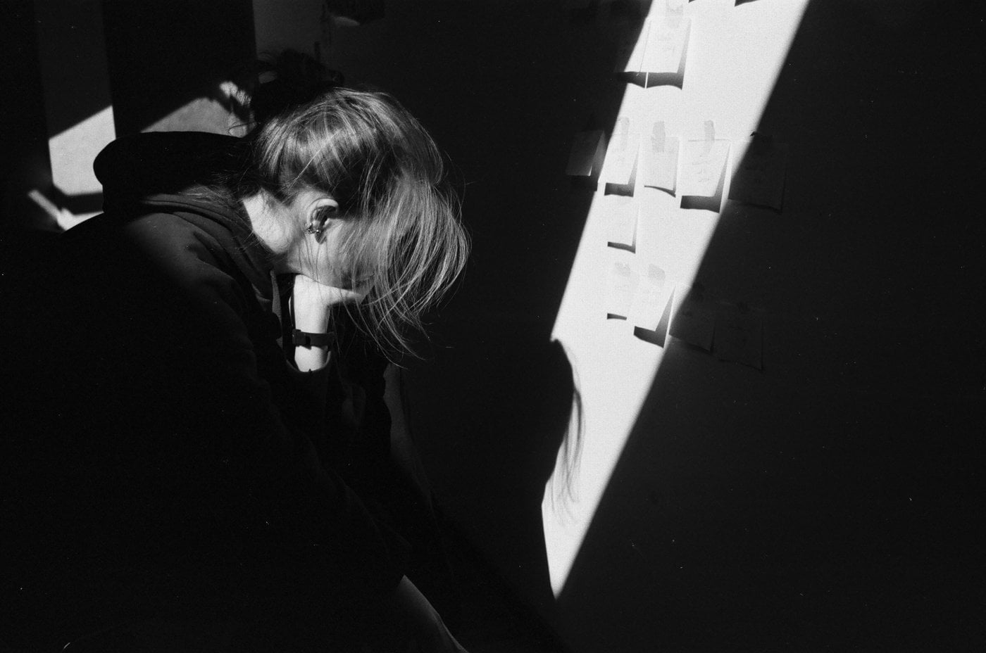 woman in black blazer leaning on white wall