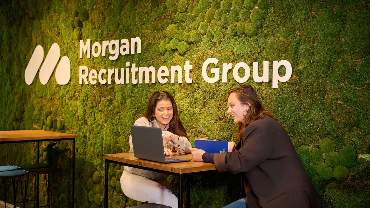 De marketing manager en corporate recruiter zijn samen in overleg op locatie amsterdam bij de logo muur