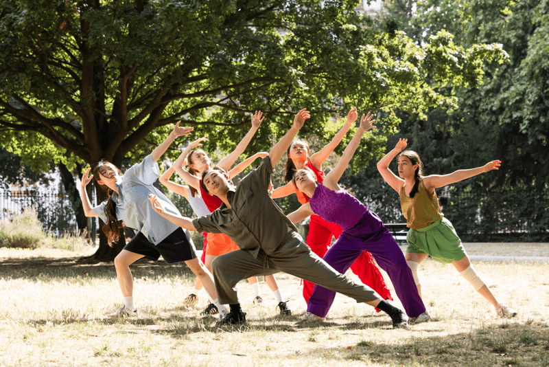 A group of dancers wearing bright costumes in the park.