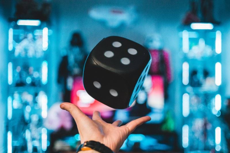 WKND iGaming. Person's left palm about to catch black dice