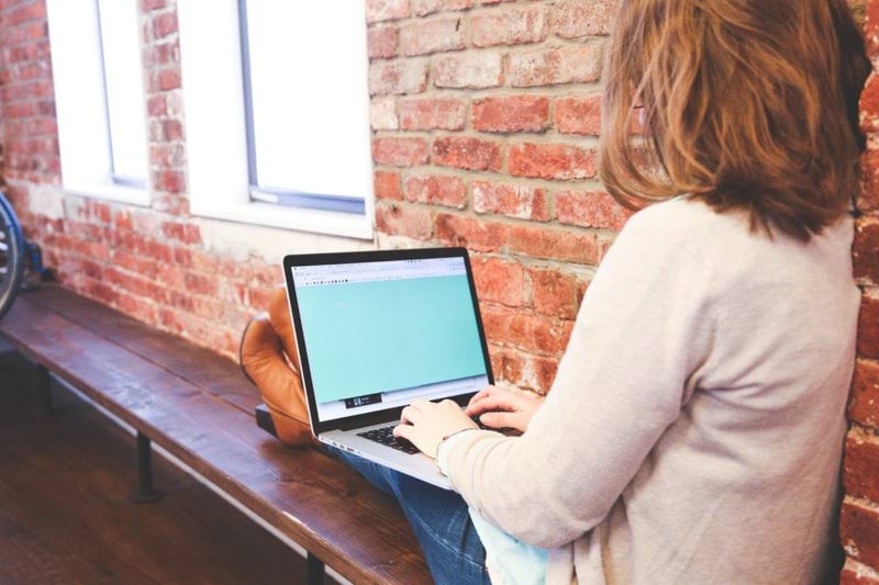 Person sitting with a laptop on their lap