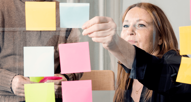 Kvinna som sätter upp post-it-lappar i olika färger.